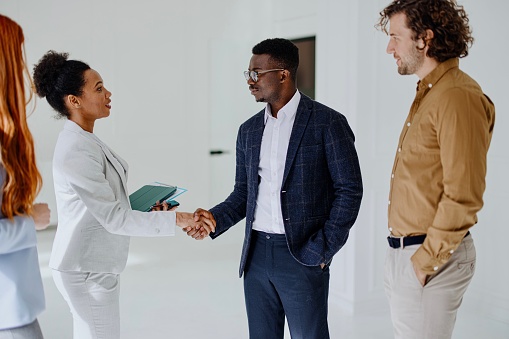 Real estate agent showing a new empty office space to business partners. Group of three young business people searching commercial real estate for their company.