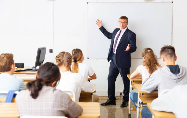istock Man teacher with notebook is giving interesting lecture for students in classroom 1319112400