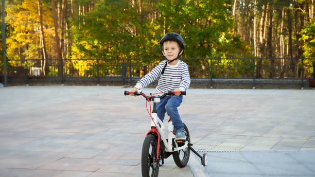 istock Happy little boy in helmet enjoying riding bicycle at park 1319112486