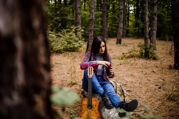 A happy woman enjoys nature, sits in a forest with tall trees, leads a healthy lifestyle away from city noise. A young woman enjoys a beautiful spring day in nature - Eastern Serbia.
