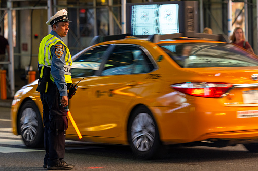A NYPD traffic officer in the middle of Times Square at night directing traffic.