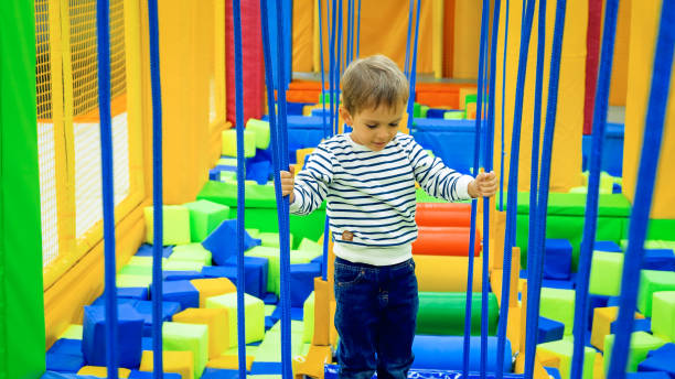 menino concentrado se equilibrando em cordas e pontes em brinquedos infantis em shopping - child swing swinging balance - fotografias e filmes do acervo