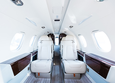 Interior of empty private jet. White seats in corporate airplane. It is representing business travel.