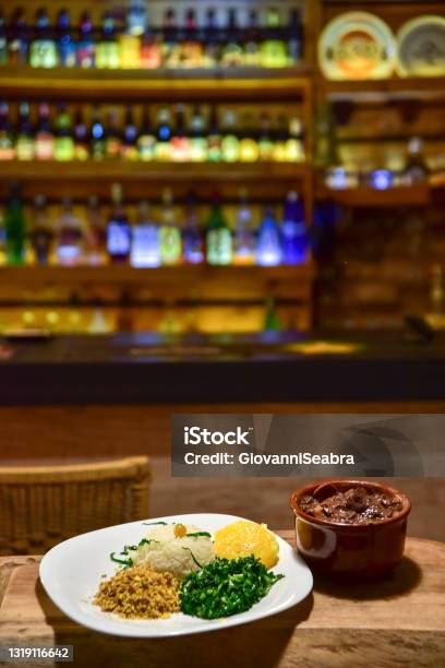 Brasilianska bönor och fläsk feijoada, med rismjöl sallad över träbit med oskärpa - Bildbanksbild...