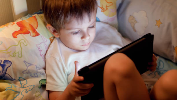 istock Closeup photo of little boy going to sleep and browsing internet on digital tablet computer 1319117313