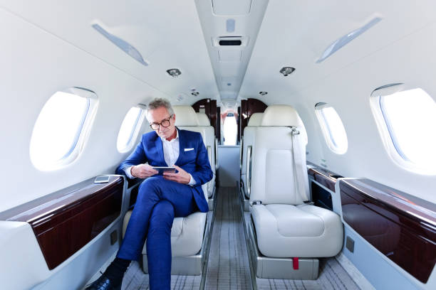 biznesmen za pomocą tabletu pc w prywatnym samolocie - vehicle interior corporate jet jet private airplane zdjęcia i obrazy z banku zdjęć
