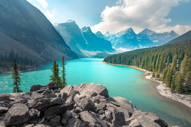 Moraine Lake in Banff National Park on a partly cloudy summer day. Mountain range in the back in a soft haze. Wind chases clouds across the sky. Hiking in the Canadian Rockies. stock photo