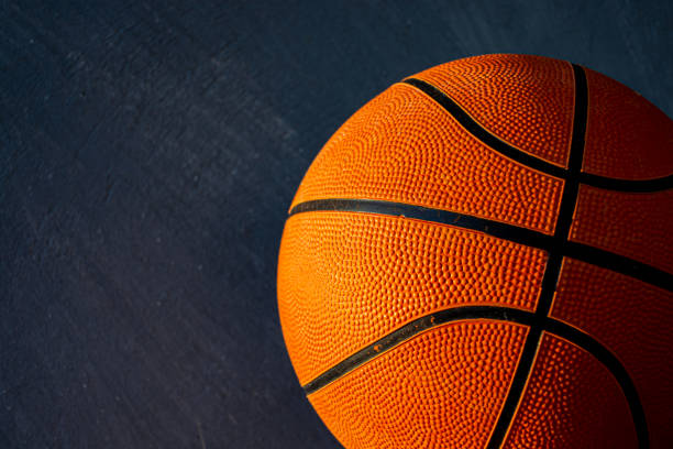 istock A basketball ball lit by sunlight on a dark concrete background. Selective focus. 1319119996