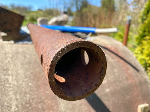 Rusty iron metal industrial pipe of large diameter old with holes for pumping liquid and construction in an oil refinery, petrochemical plant.