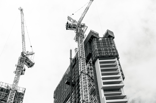 Black and white Tower cranes at construction site, sky background with copy space, full frame horizontal composition