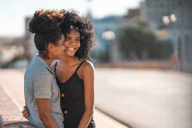 молодые женщины пара в городе в солнечный день - lesbian homosexual kissing homosexual couple стоковые фото и изображения