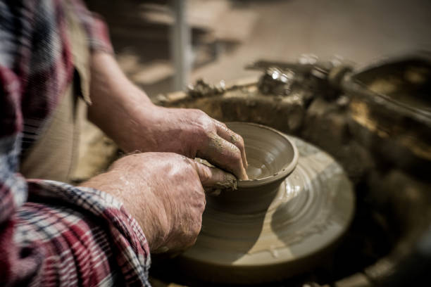 istock Close-up of a craftsman's hands while making a bowl on a pottery wheel 1319131617