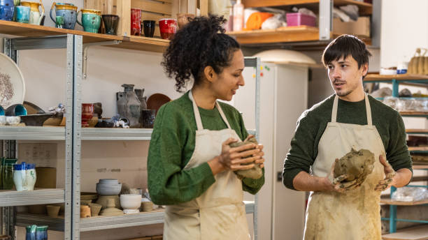 istock Pottery instructor teaching his student how to knead clay 1319131618