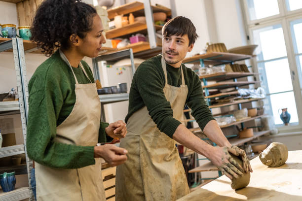 istock Pottery instructor teaching his student how to knead clay 1319131622