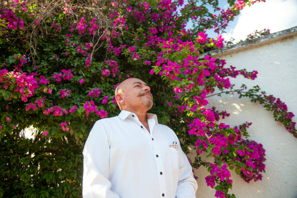 Older man under a buganvilia tree Older man under a bougainvillea tree buganvilia stock pictures, royalty-free photos & images