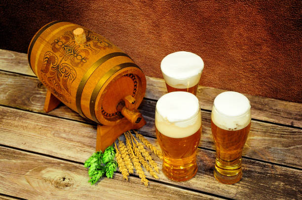 trzy szklanki lekkiego piwa, drewniana beczka, chmiel i słód na drewnianym stole. - draught beer variation three objects zdjęcia i obrazy z banku zdjęć