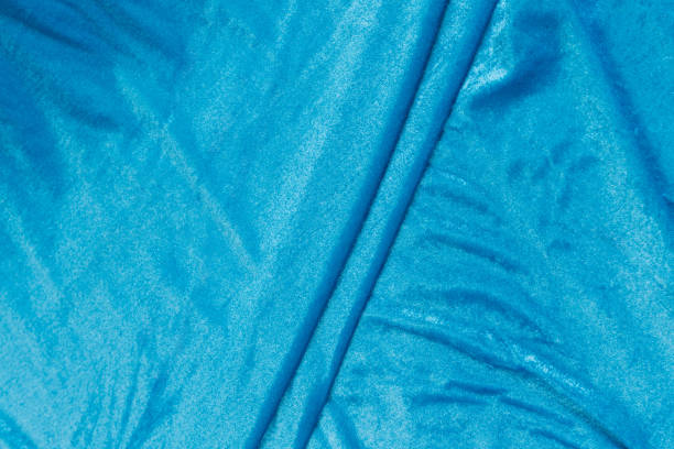 istock Colored blue textile satin fabric folded in folds and waves with highlights and texture 1319156635