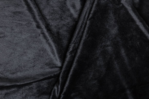 istock Colored black textile satin fabric folded in folds and waves with highlights and texture 1319156654