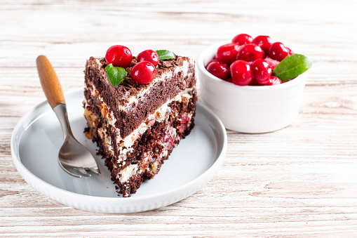 Chocolate sponge cake with cherries on a plate. Copy space