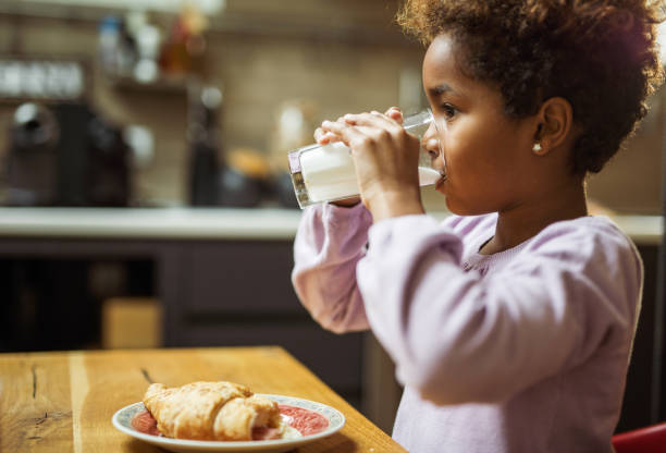istock Small black girl drinking milk during breakfast time at home. 1319166668