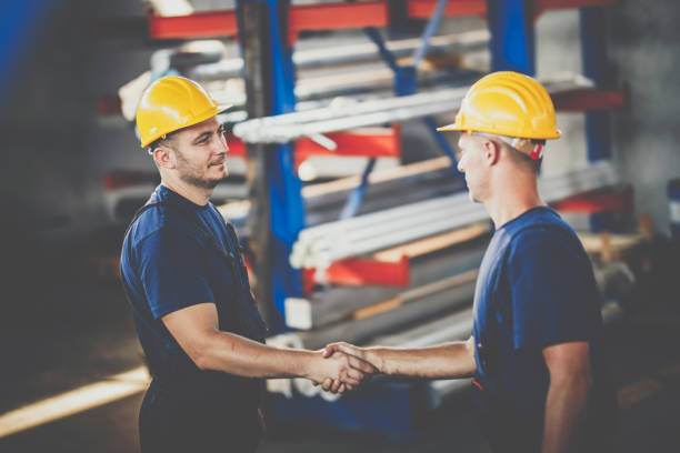 istock Metal workers talking while shaking hands in industrial building. 1319166855