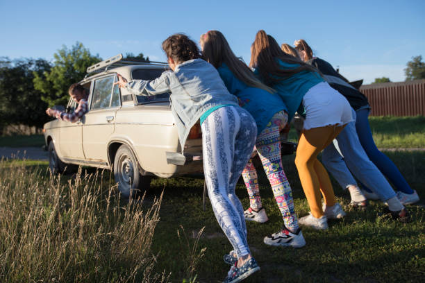 Young cheerful girls are pushing an old car. Women in the style of the 90s. Young cheerful girls are pushing an old car. Women in the style of the 90s. pushing photos stock pictures, royalty-free photos & images