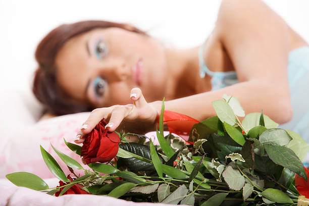 istock Young woman lying on bed with red roses 131917098