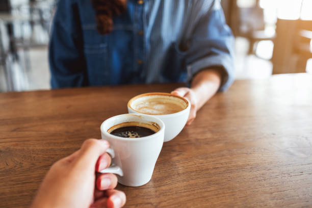 istock a woman and a man clinking coffee cups together in cafe 1319172530