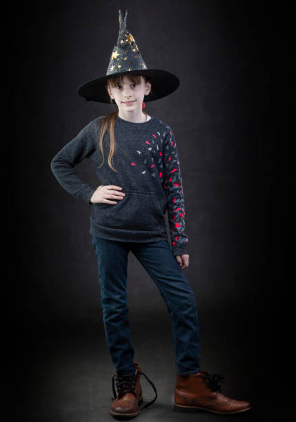 istock Little girl wearing a witch hat on a dark background. 1319173709