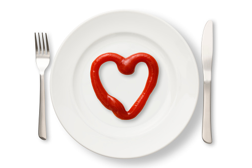 Overhead shot of white plate on heart-shaped ketchup, isolated on white with clipping path.