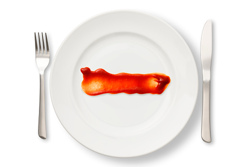 Overhead shot of white plate on ketchup, isolated on white with clipping path.