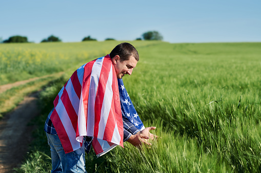 Young man with an American flag in a wheat field