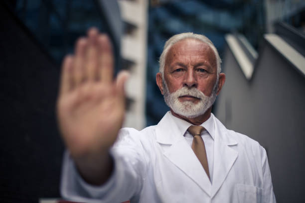 Mature serious doctor. Gesturing with hand. Stop sign with hand.