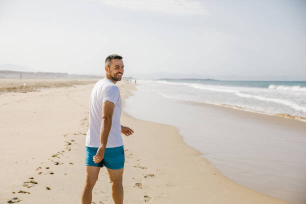 istock Young man running on the beach 1319182288