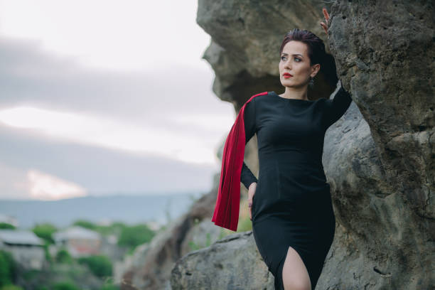 istock Mysterious queen woman with red mantle leaning on old huge cliffs 1319183447