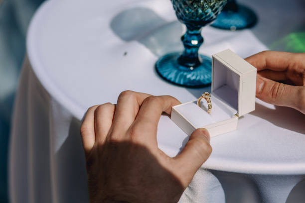 istock Engagement ring with opened box on table. Guy holding engagement ring 1319183493