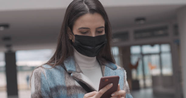 istock Woman with face mask using a smartphone 1319183868