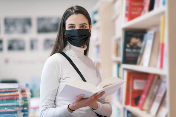 istock Young woman with face mask in a bookstore 1319184810