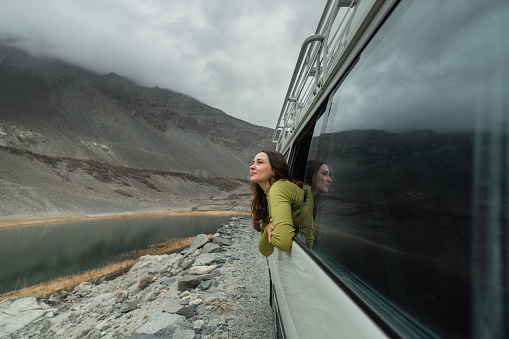 Young Caucasian woman looking at mountains of Northern Pakistan from window in the van