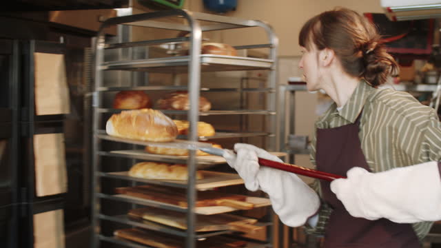 Female Baker Taking Hot Bread from Oven with Shovel