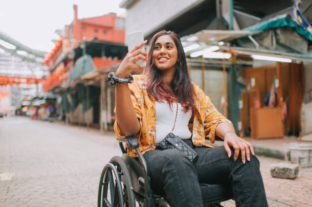 asian indian beautiful woman with disability using wheelchair exploring downtown district in kuala lumpur asian indian beautiful woman with disability using wheelchair exploring downtown district in kuala lumpur accessibility for persons with disabilities photos stock pictures, royalty-free photos & images