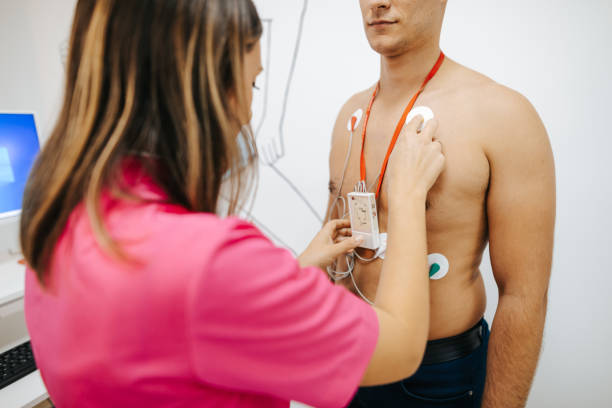 Preparing young male patient for heart stress test on treadmill Female nurse is putting Holter monitor on the chest of young male patient at cardiology clinic, preparing him for a stress test on a treadmill stress test stock pictures, royalty-free photos & images