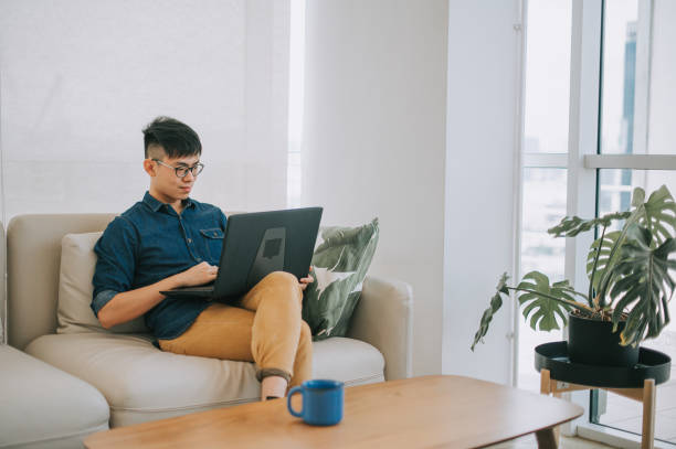 istock asian chinese young man studying using laptop at home sitting on sofa 1319197184