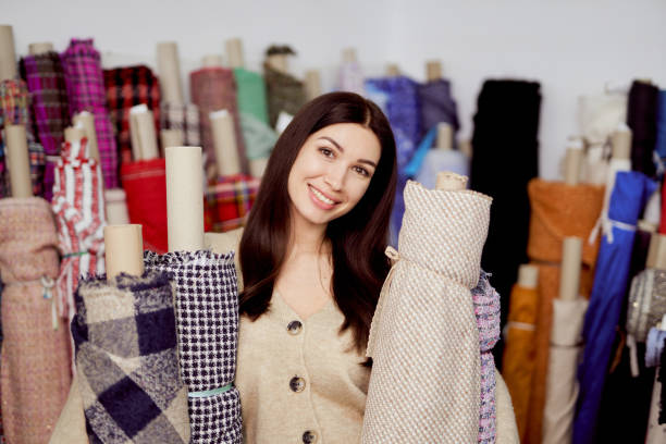 istock Attractive smiling seamstress or tailor hugs textile rolls 1319198611
