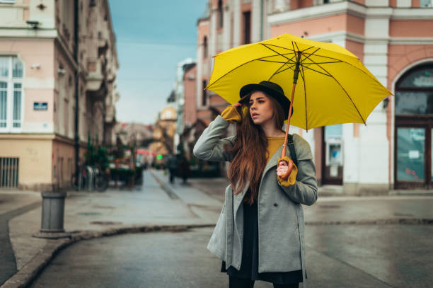 istock Young beautiful woman using a smartphone outside on a rainy day 1319200273