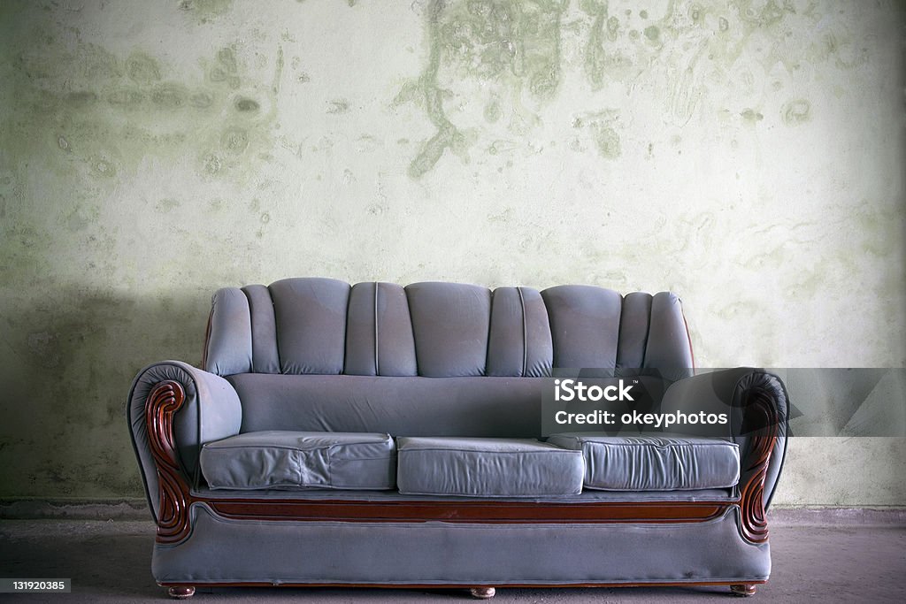 Sofa Blue and disty sofa infront of old green wall. Old Stock Photo