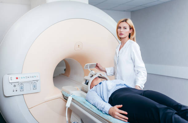 istock Radiologic model technician help at mature female patient lying on a CT Scan bed and looking at the camera 1319204350