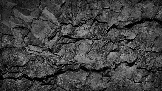 Black white grunge background. Rock texture with cracks. Stone wall background with copy space for text and design. Web banner. Dack gray rocky surface. Close-up.