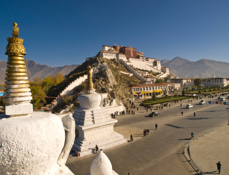 Potala Palace,ex-residence of Dalai Lama, now a museum. At left, a golden chorten (or stupa). Wide street with people in front, High angle,  Lhasa, Tibet.