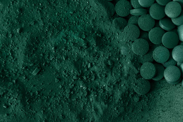 Green spirulina algae tablets and powder nutritional supplement macro close up top view. stock photo